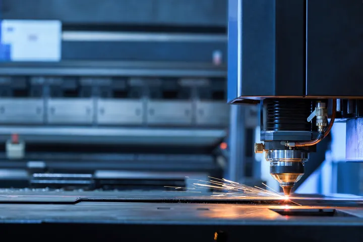 A fiber laser cutting head at work with an idle mechanical shear behind it